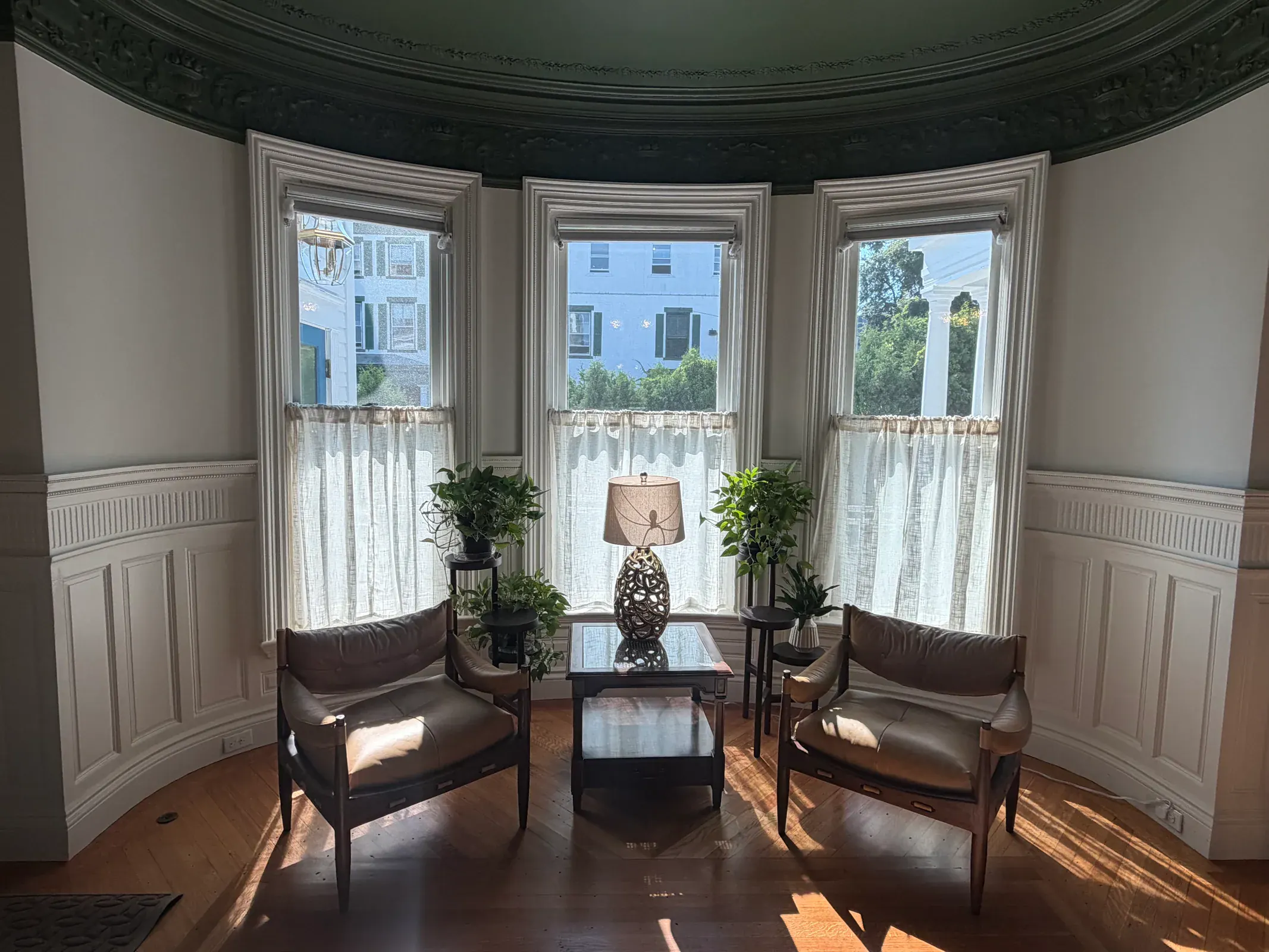A sunlit bay-window seating area at The Delphian with carved trim and hardwood floors